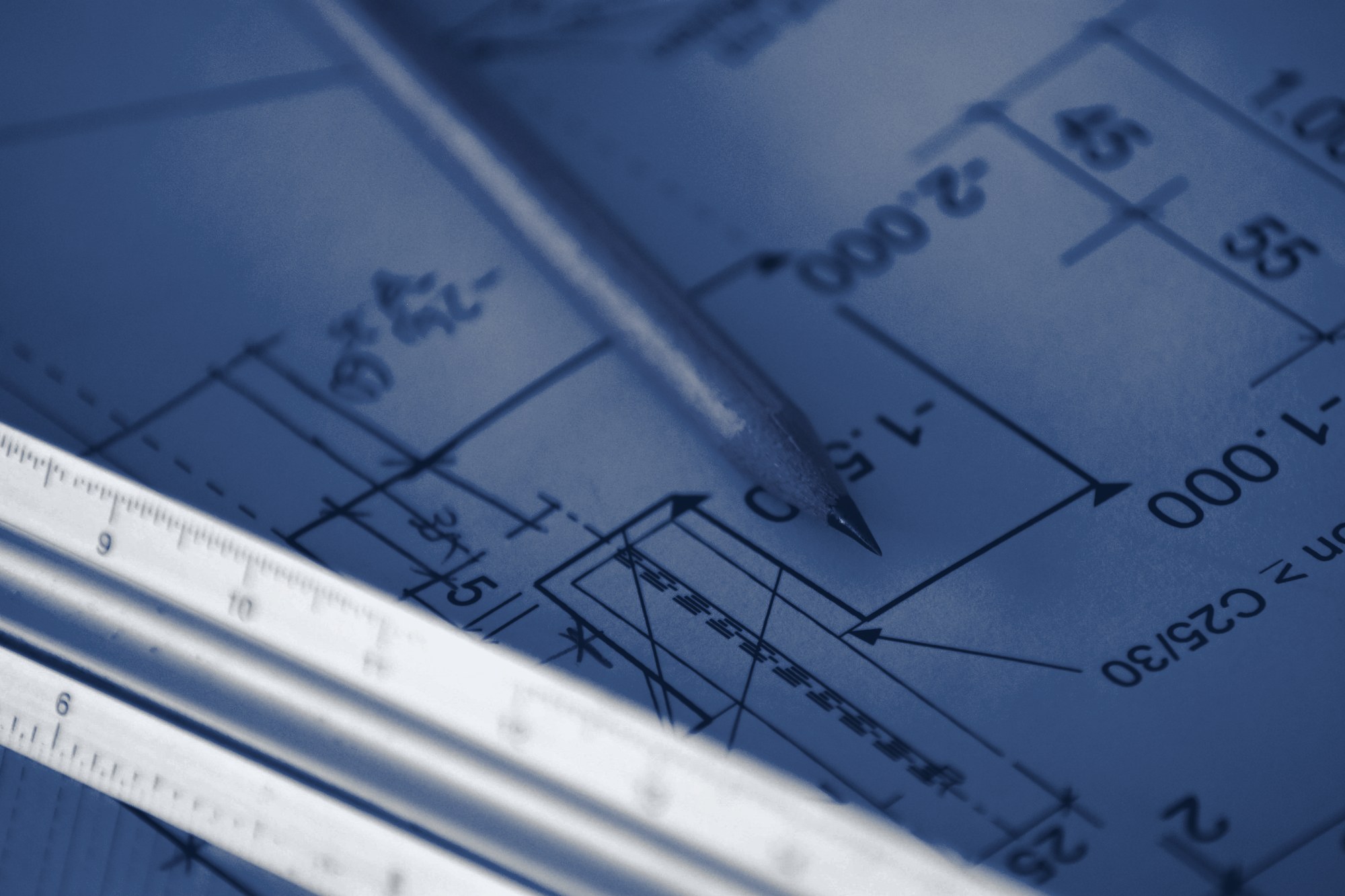 Close-up of a technical drawing with a pencil and scale ruler on a desk, tinted navy