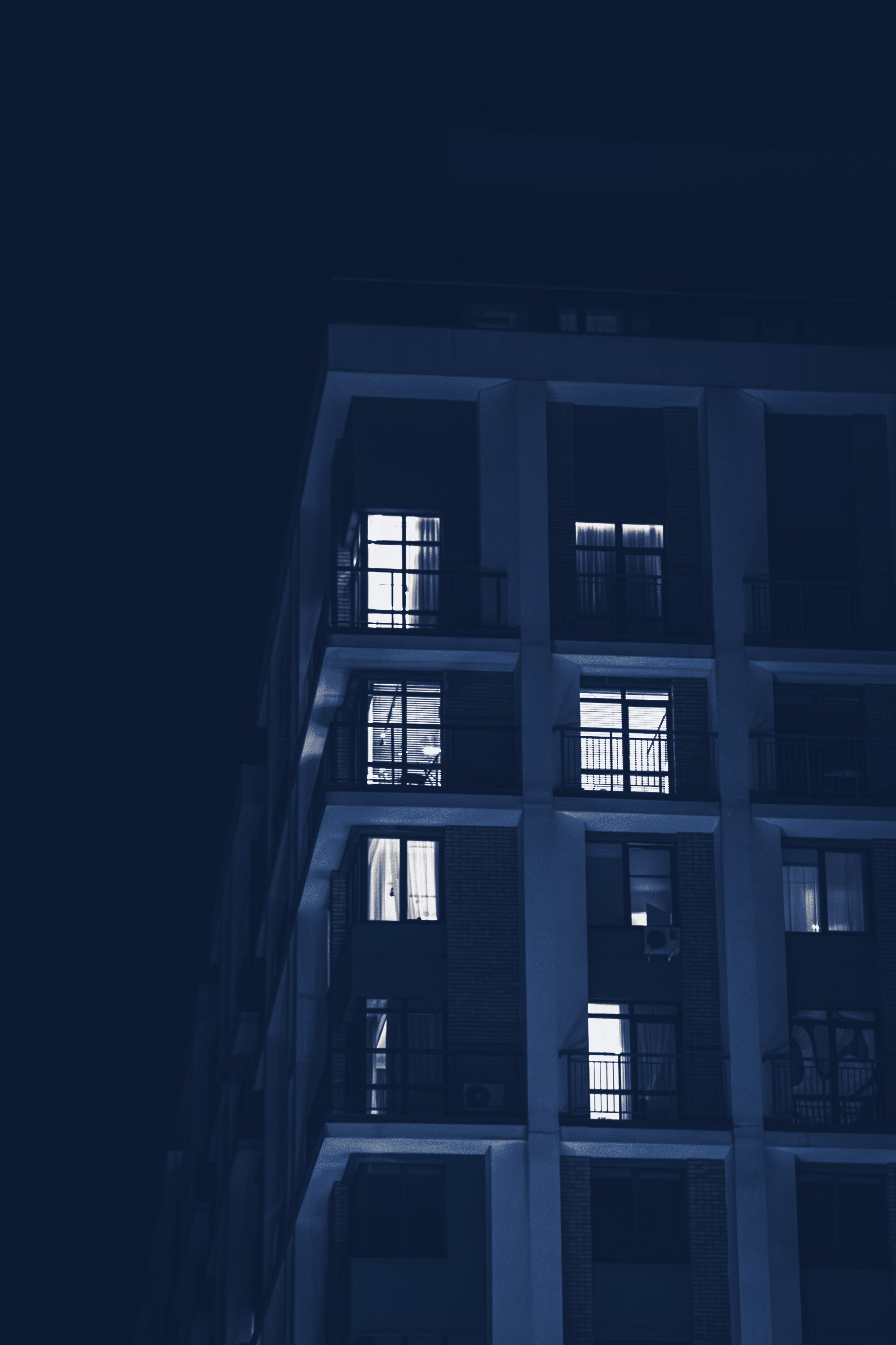 Apartment building lit at night, tinted navy